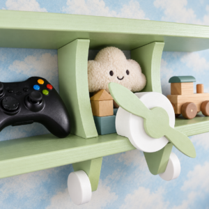 Close-up of green wooden aeroplane wall shelf styled with children’s toys